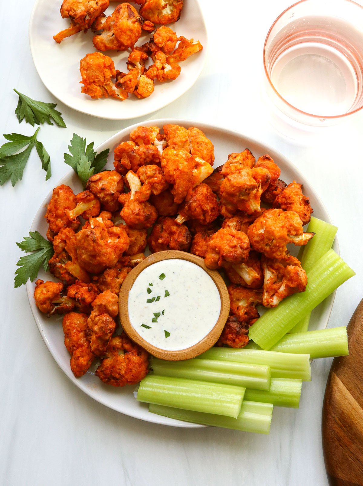 Air fryer buffalo cauliflower served on a plate with celery and dip.