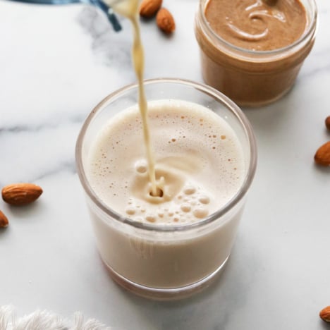 almond milk poured into a glass from a blender.