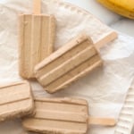 banana popsicles on a parchment lined plate.