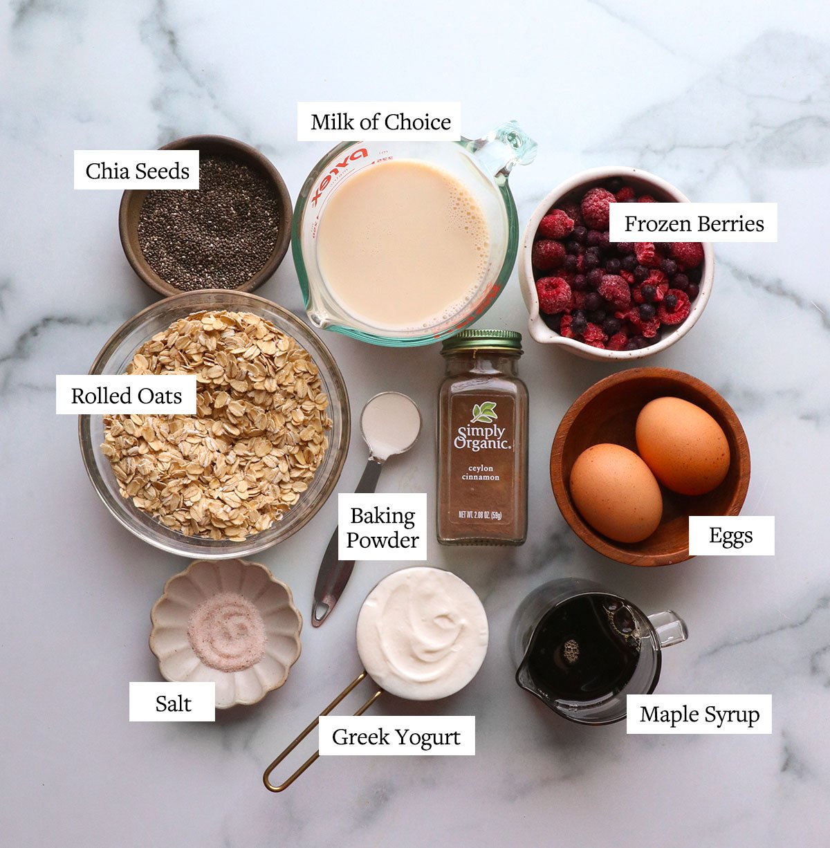 oats, chia seeds, frozen berries, milk and eggs labeled on a white surface.