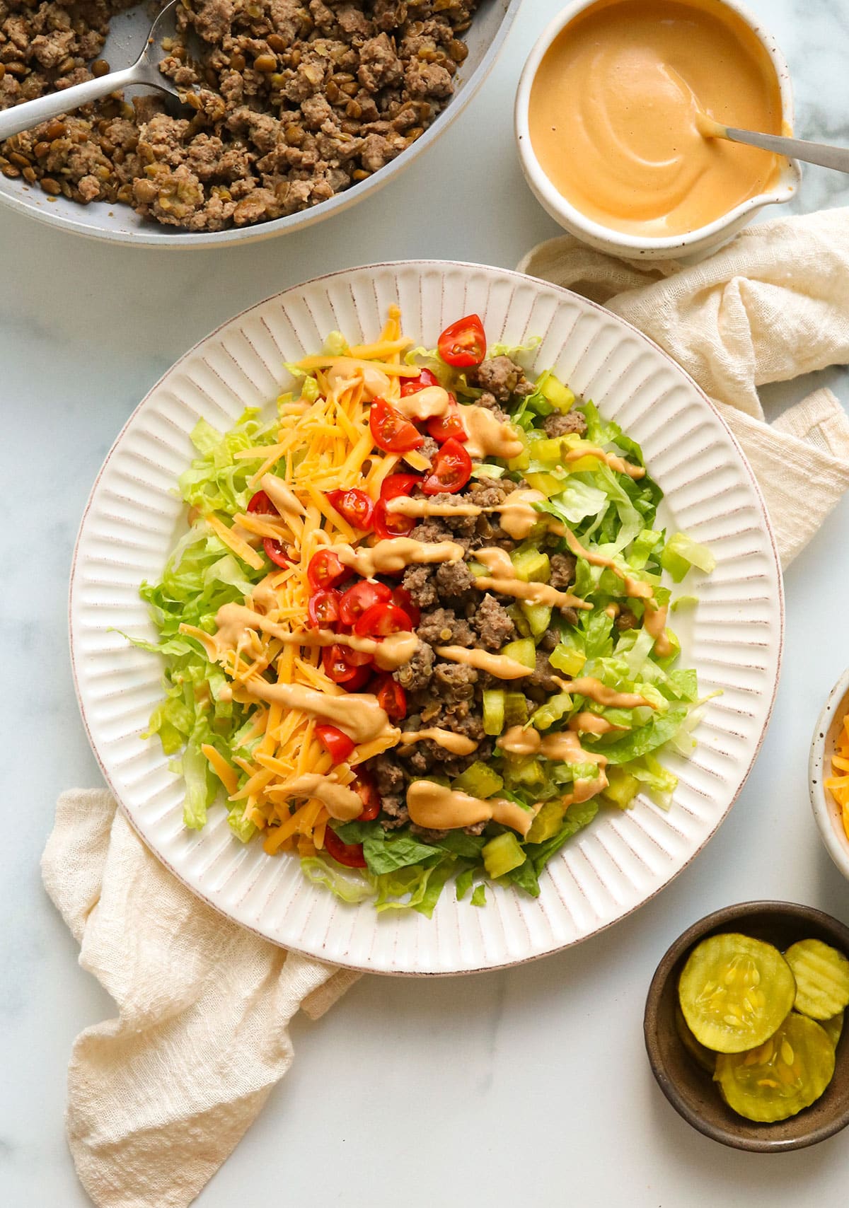 big mac salad drizzled with burger sauce on a white plate.