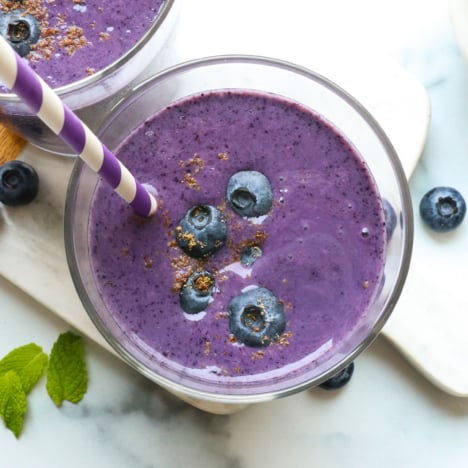 blueberry smoothie in two glasses with a straw.