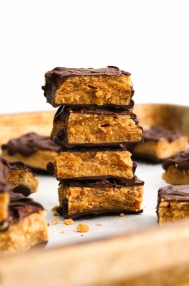 homemade butterfingers stacked on a baking sheet with white background.