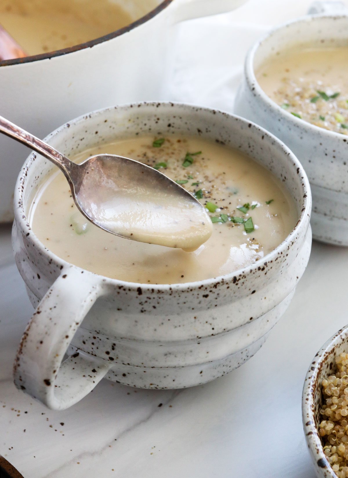 cauilflower soup lifted up on spoon from mug