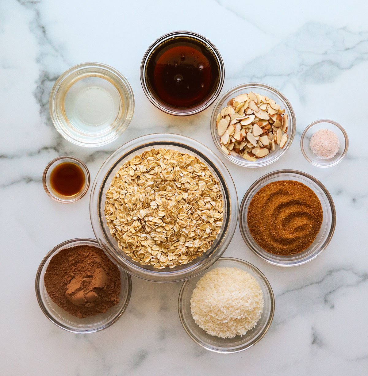 chocolate granola ingredients in a glass bowl on a marble surface.