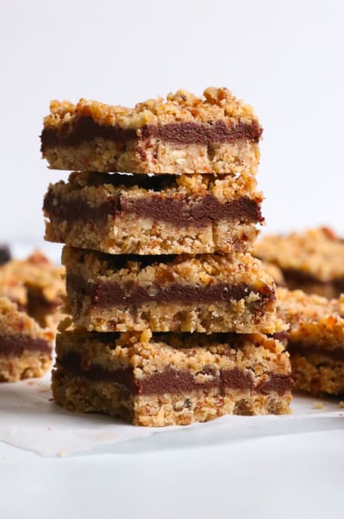 chocolate walnut bars stacked on white parchment paper.