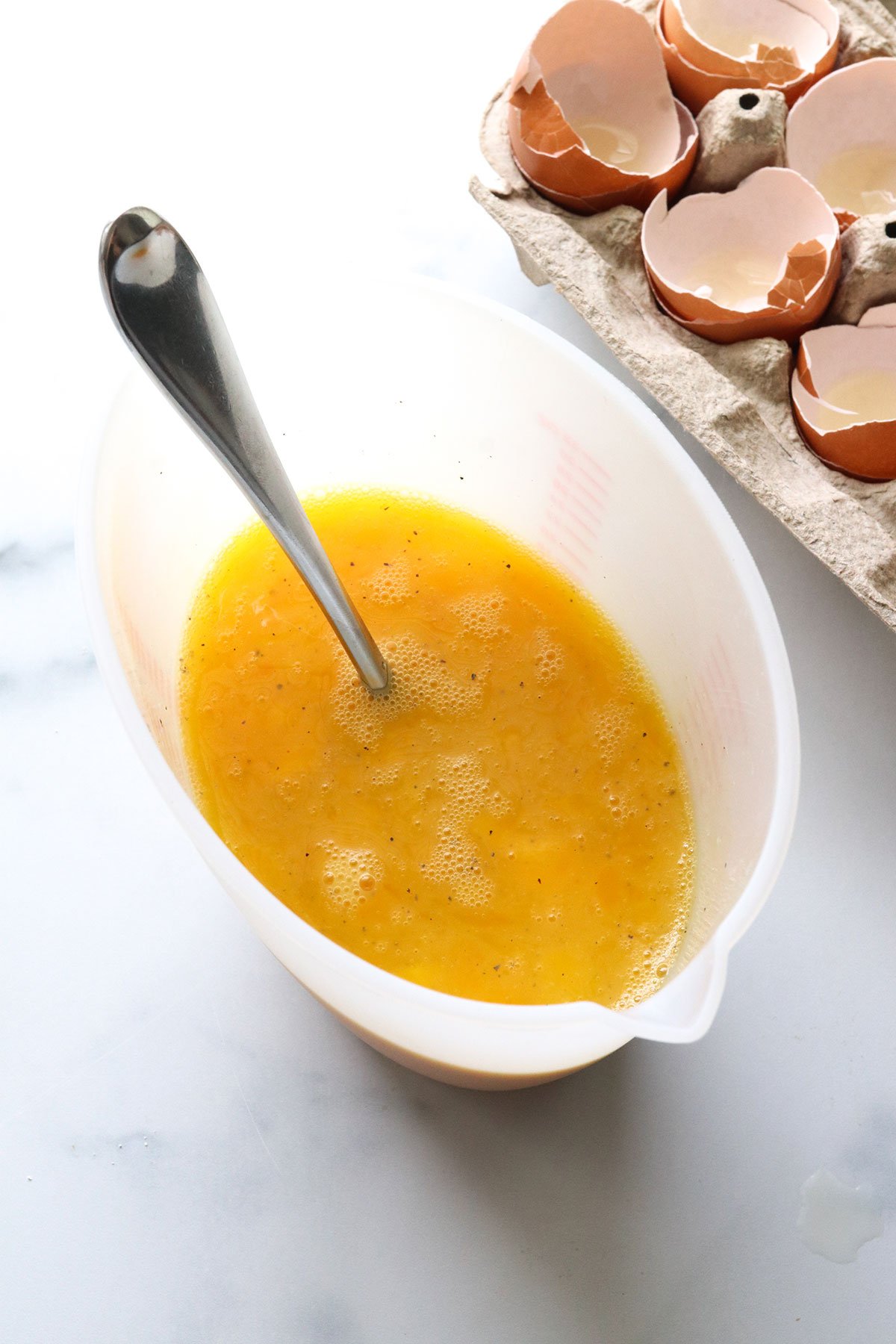 eggs, salt, and pepper mixed with a fork in a measuring cup.