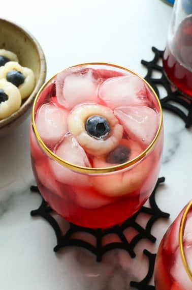 lychee eyeballs floating in a red punch glass with ice.