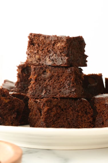 flourless sweet potato brownies stacked on a white plate.