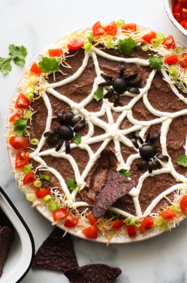 Halloween bean dip with spider web and olive spiders on top.