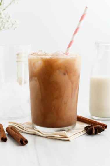 iced chai latte in a glass with a striped pink straw.