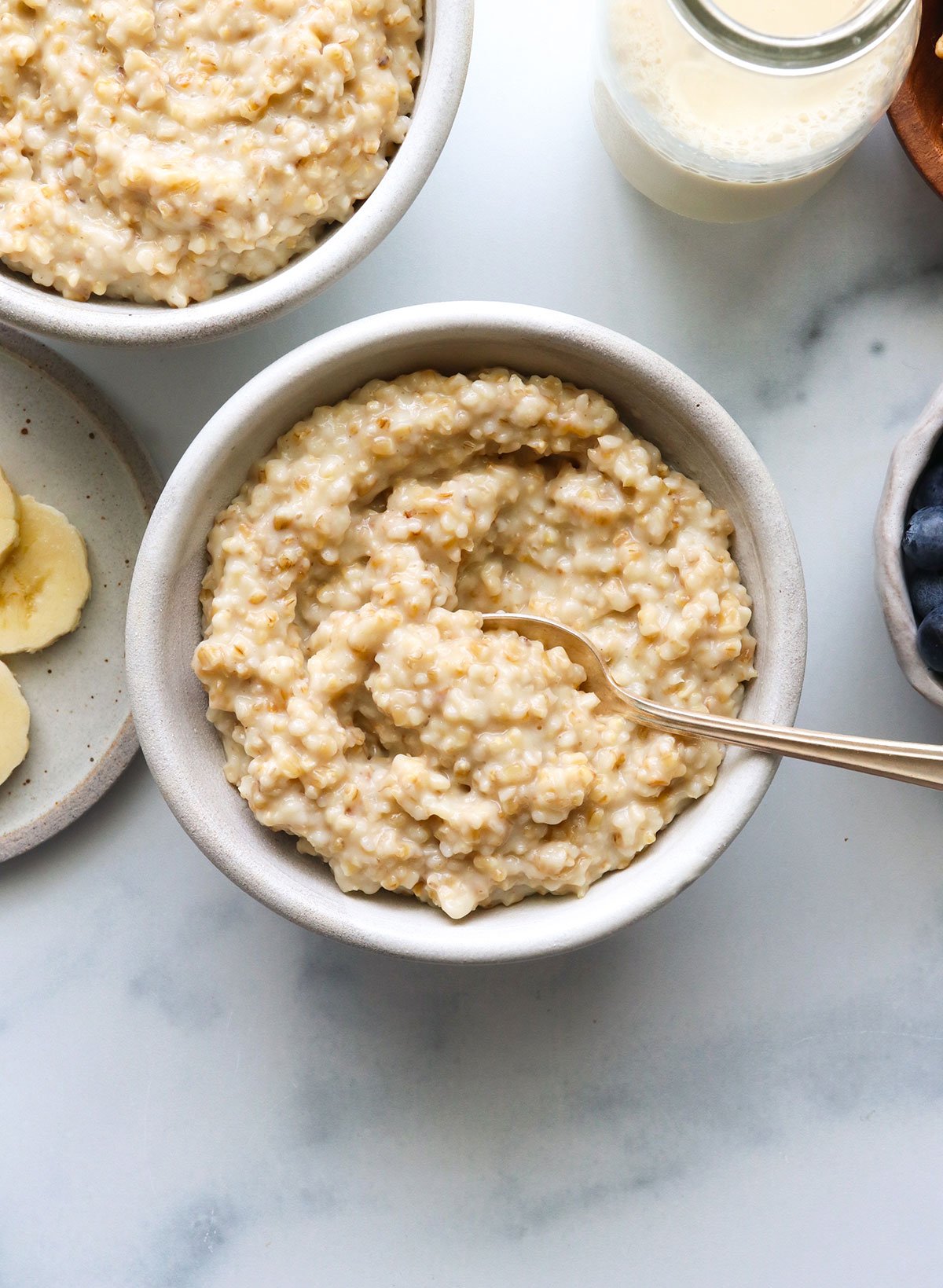 plain steel cut oats served in two white bowls with a spoon.