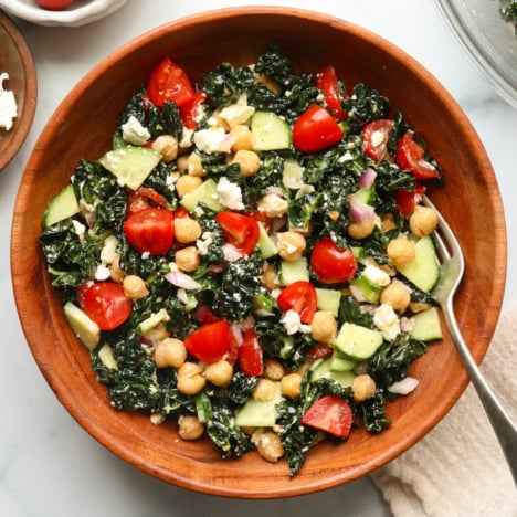 kale feta salad served in a wooden bowl with a fork.