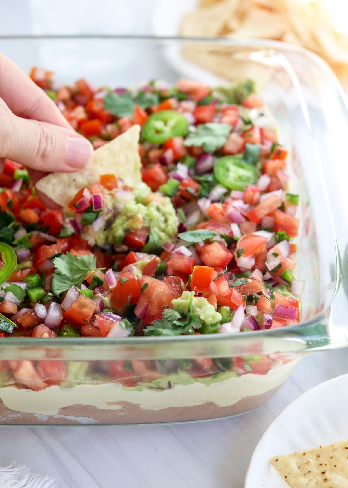 chip dipped into a dish of vegan 7 layer dip.