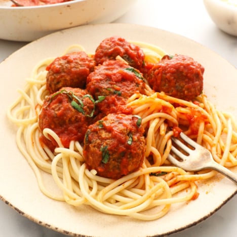 lentil meatballs in marinara sauce on a plate of spaghetti noodles.