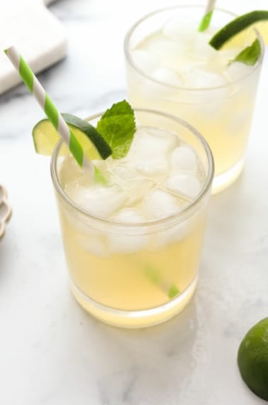 mojito mocktail in two glasses with lime and mint garnish.