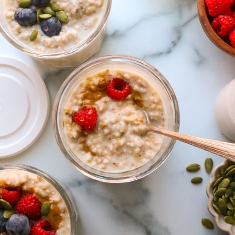 overnight steel cut oats in 3 glass jars topped with berries.