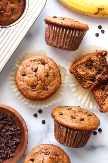 peanut butter banana muffins topped with chocolate chips on a white surface.