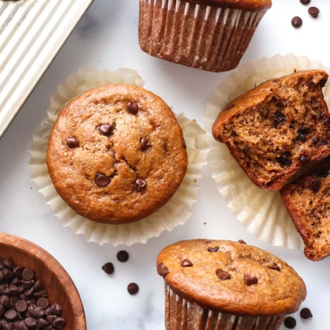 peanut butter banana muffins topped with chocolate chips on a white surface.