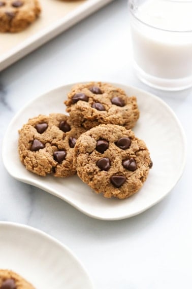 protein cookies arranged on a white plate with a glass of milk.