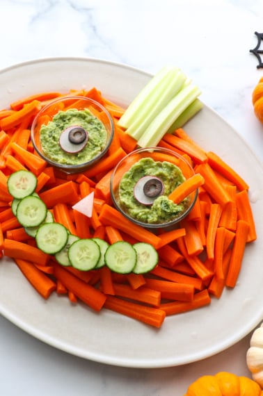 veggies arranged on a platter to look like a pumpkin with eyes and smile.