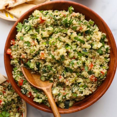 quinoa tabbouleh served in a wooden bowl with a wooden spoon.