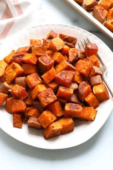 roasted sweet potato cubes served on a white plate with a fork.