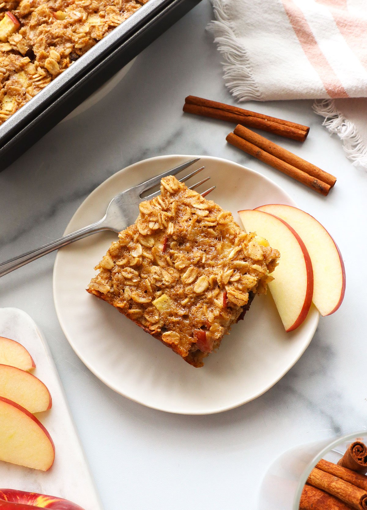 slice of apple baked oatmeal on a white plate with a fork.