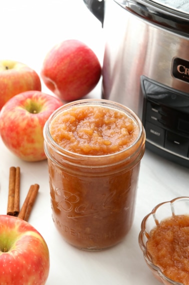 slow cooker applesauce stored in a glass jar near apples.