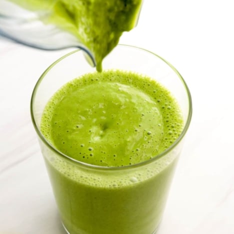 green smoothie poured into glass from blender