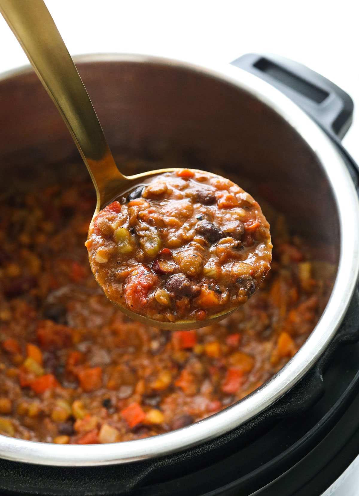 vegan chili lifted up in a ladle from the Instant Pot.