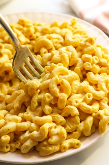 vegan mac and cheese served on a white plate with a fork.