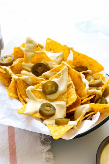 vegan nacho cheese served on tortilla chips with jalapenos.