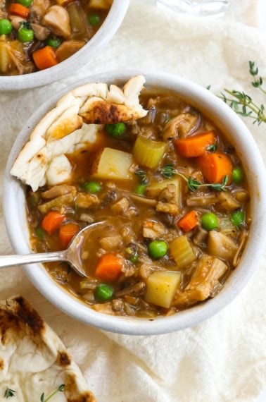 vegetable stew with a spoon and bread inside the bowl.