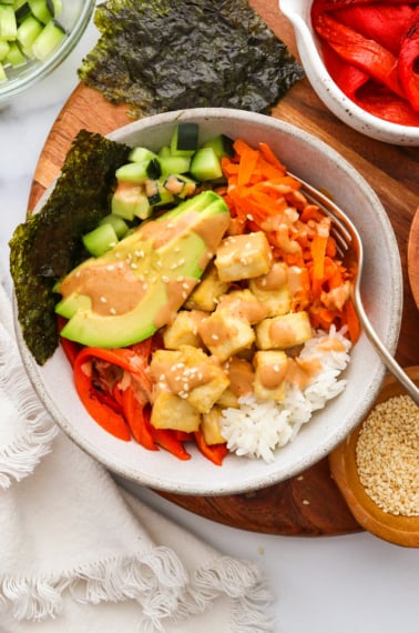 vegan sushi bowl topped with creamy tahini sriracha sauce.